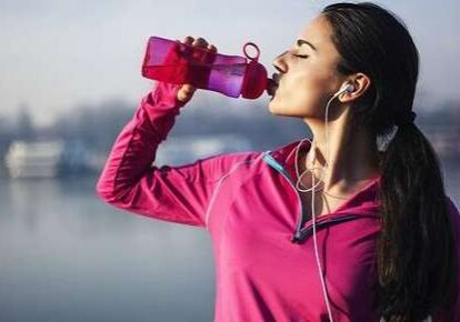 Female athlete rehydrating by a lake
