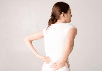 Person experiencing discomfort in the lower back.